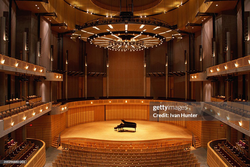 Interior of empty theater, piano at center stage, elevated view