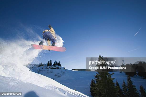 male snowboarder jumping on slope, low angle view - スノボー ストックフォトと画像