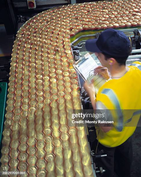 Male worker monitoring brewery production line transfering beer cans