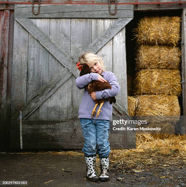 girl (5-7) hugging chicken outside barn, portrait - chicken bird stock pictures, royalty-free photos & images