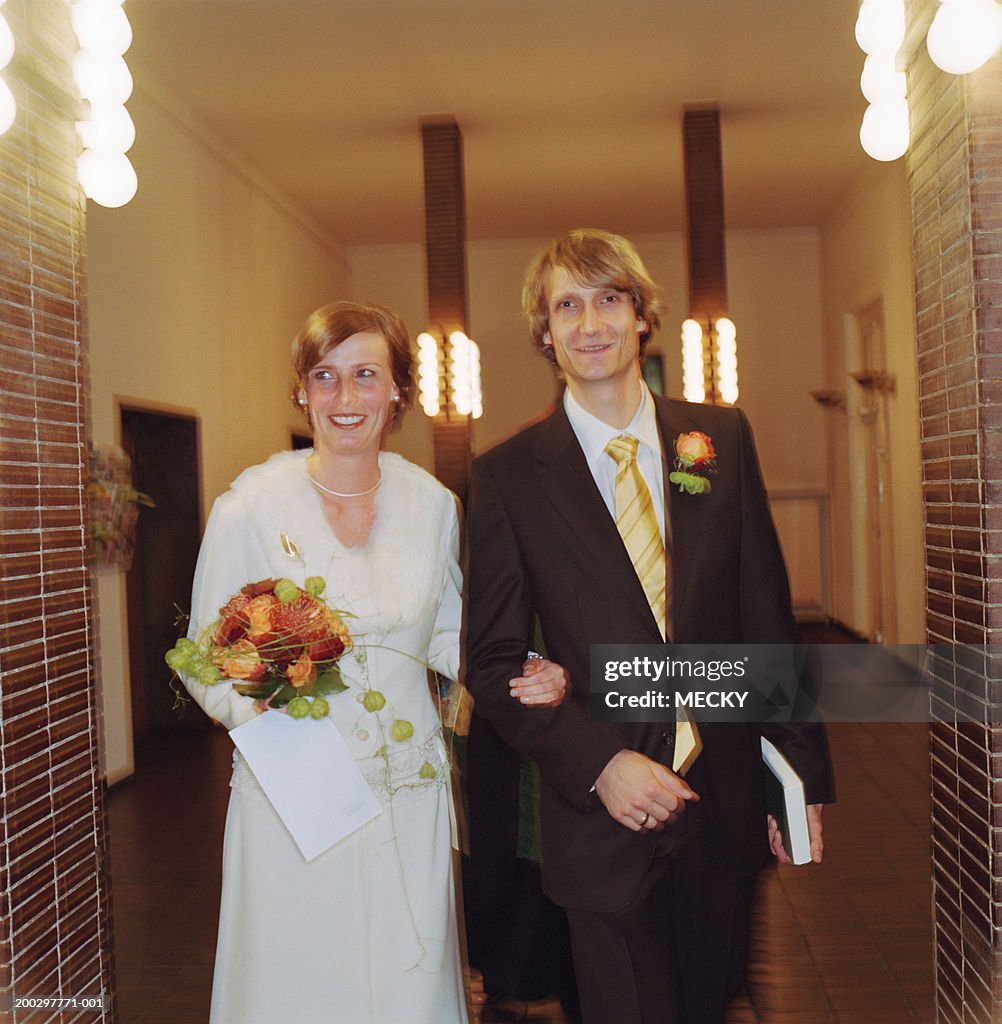 Bride and groom standing in hallway, smiling