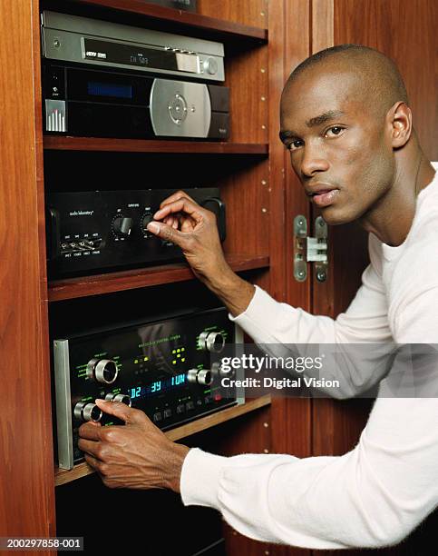young man adjusting stereo, portrait - equipo de alta fidelidad fotografías e imágenes de stock