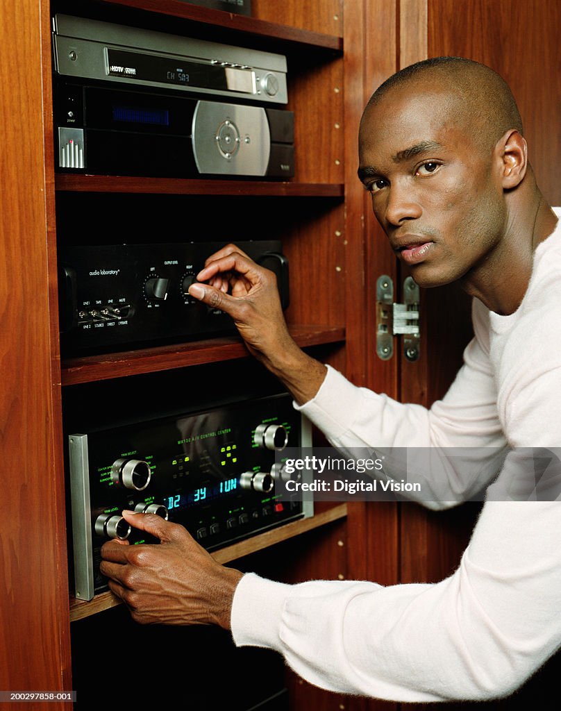 Young man adjusting stereo, portrait
