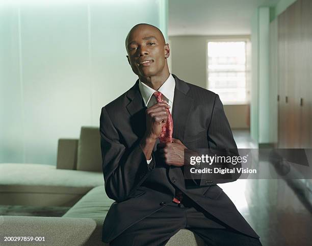 young businessman adjusting tie, smiling, portrait - adjusting suit stock pictures, royalty-free photos & images