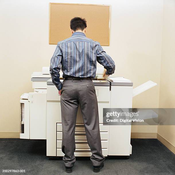 male office worker using photocopying machine, rear view - photocopier stockfoto's en -beelden