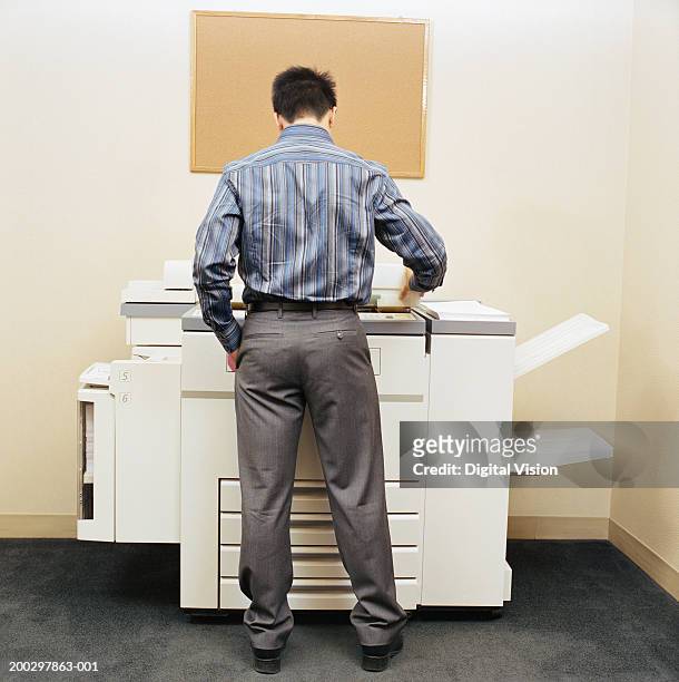 male office worker using photocopying machine, rear view - copier stock pictures, royalty-free photos & images