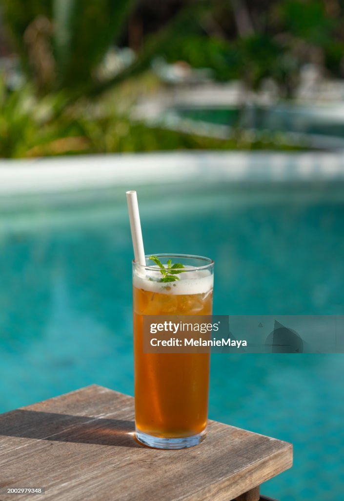 Fresh Ice Tea glass drink with mint and paper straw served at pool bar in tropical Maldives island resort