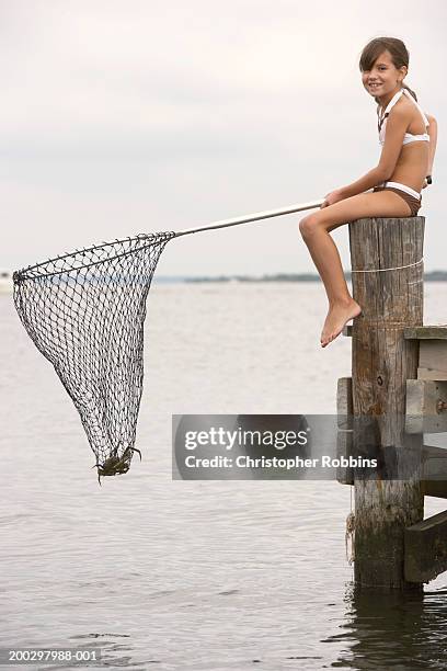 girl (8-10) on jetty holding fishing net with crab in it, portrait - fishing net stock pictures, royalty-free photos & images