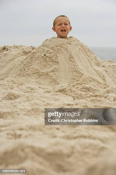 boy (2-4) buried in mound of sand, shouting, portrait - buried stock-fotos und bilder