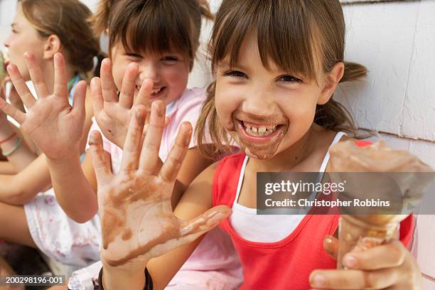 three girls (6-9) eating ice cream, two showing messy hands, portrait - girl eating messy ice cream cone stock pictures, royalty-free photos & images