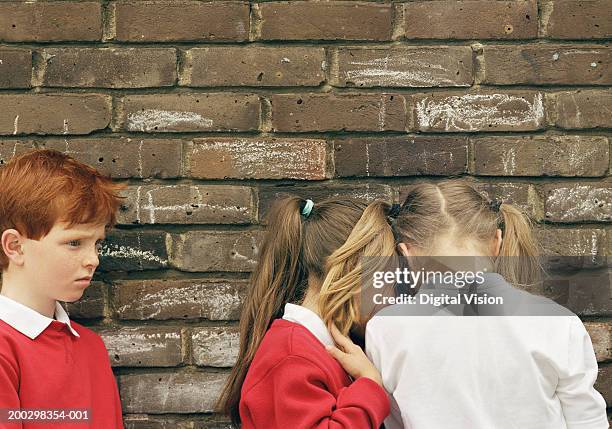 boy (5-7) and two girls (6-8) standing by wall - school exclusion stock pictures, royalty-free photos & images