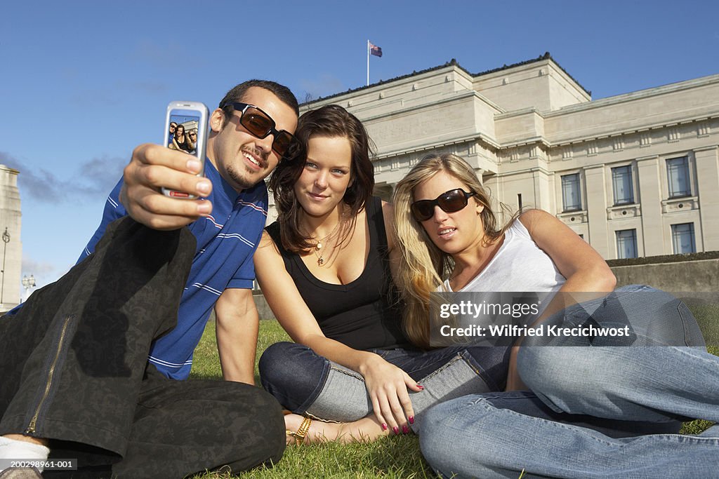 Two young women and young man taking photo of themselves, smiling