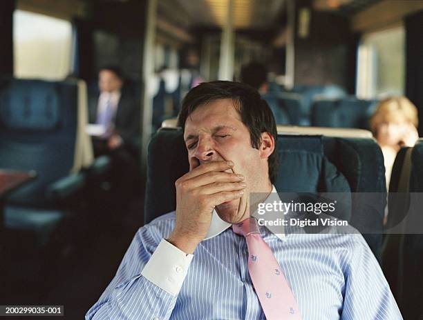 businessman yawning on train (focus on man) - yawning stock pictures, royalty-free photos & images