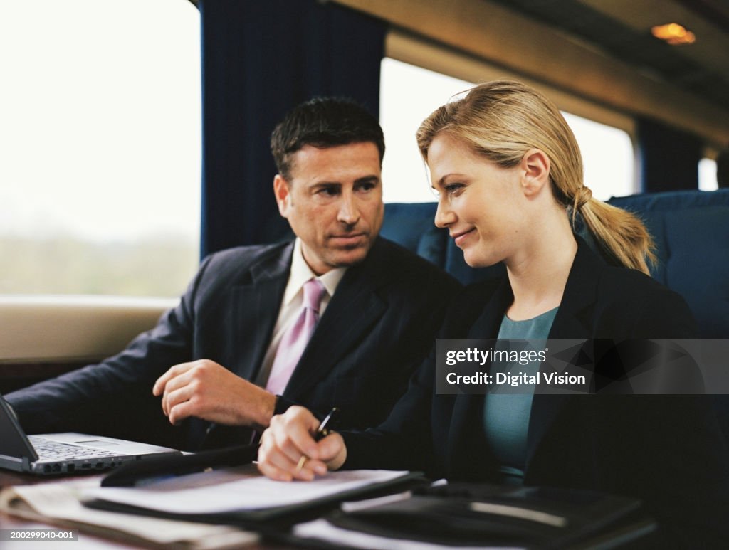 Businessman and businesswoman working together on train