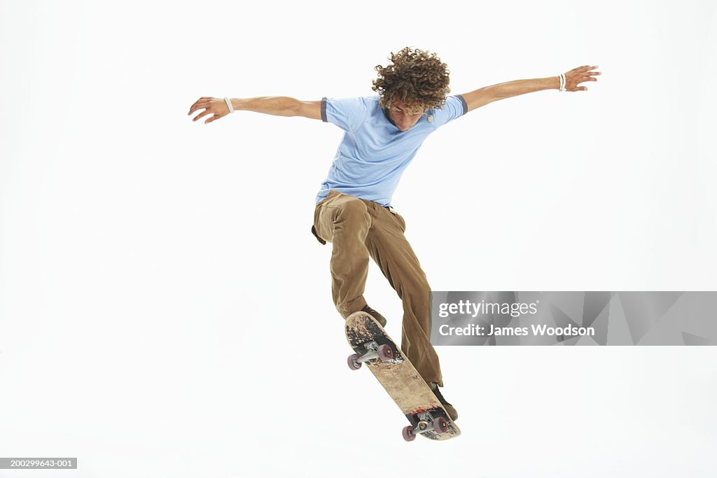 Teenage boy (16-18) practicing skateboard trick, arms outstretched
