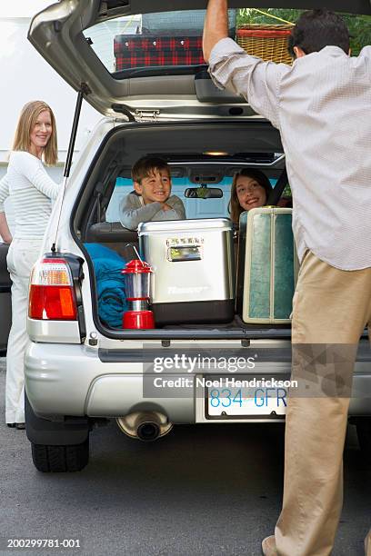 mother getting into car, boy and girl (8-13 years) on back seat watching father close boot lid - closing car boot fotografías e imágenes de stock