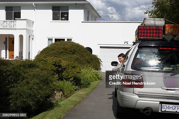 man looking out of window of car on front drive, smiling - car leaving stock pictures, royalty-free photos & images