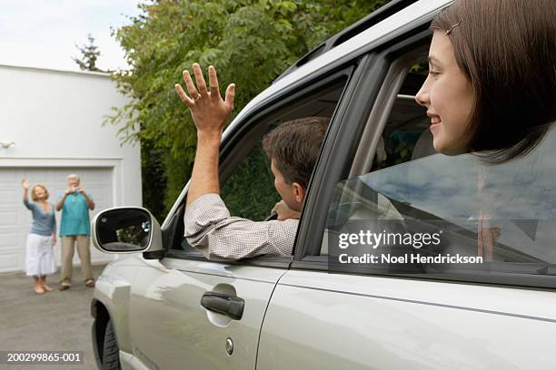 man and daughter (13-15 years) in car waving to senior couple on drive - 40 44 years woman caucasian stockfoto's en -beelden