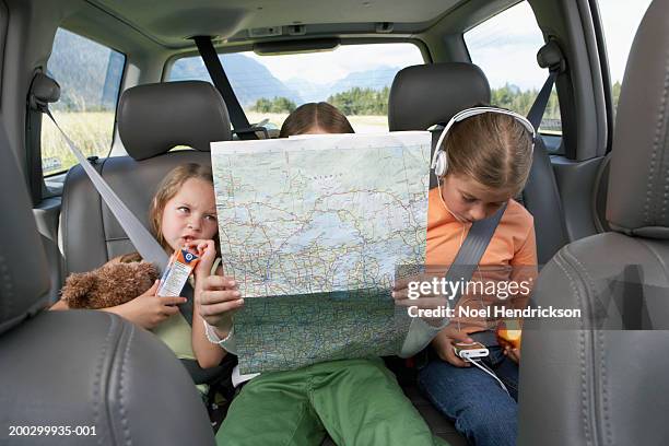 three girls (6-8 years) sitting on rear seat of car on road trip - car journey stock-fotos und bilder