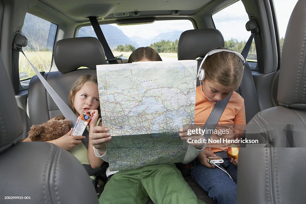 Three girls (6-8 years) sitting on rear seat of car on road trip