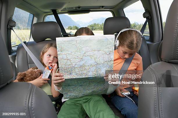 three girls (6-8 years) sitting on rear seat of car on road trip - road trip stock pictures, royalty-free photos & images