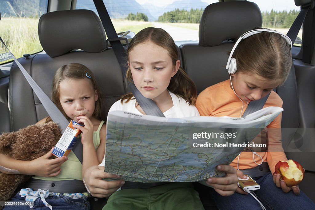 Three girls (6-8 years) sitting on rear seat of car during road trip