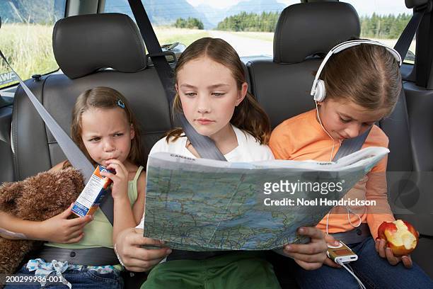 three girls (6-8 years) sitting on rear seat of car during road trip - juice carton 個照片及圖片檔