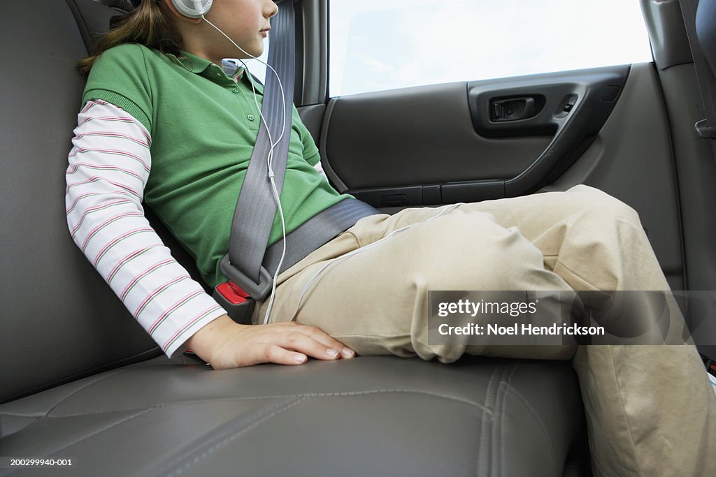 Girl (6-8 years) sitting on rear seat of car, close-up, side view