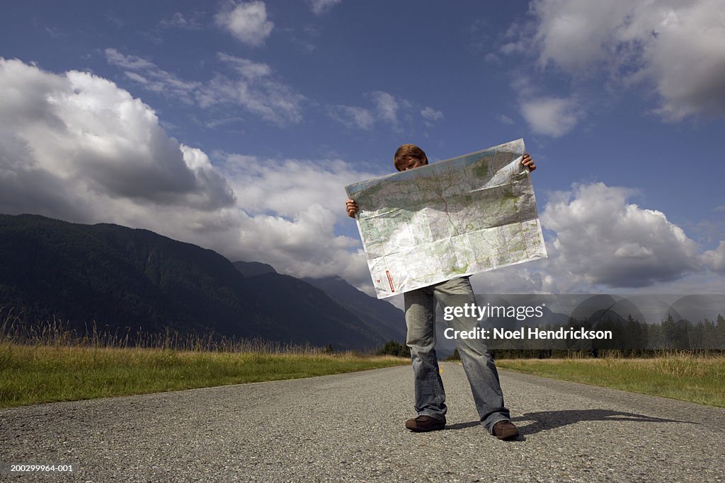 Man standing on rural road reading road map