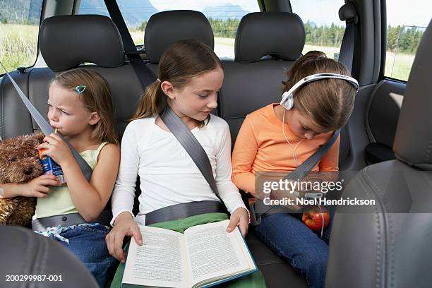 three girls (6-8 years) sitting on rear seat of car on road trip - long journey stock pictures, royalty-free photos & images