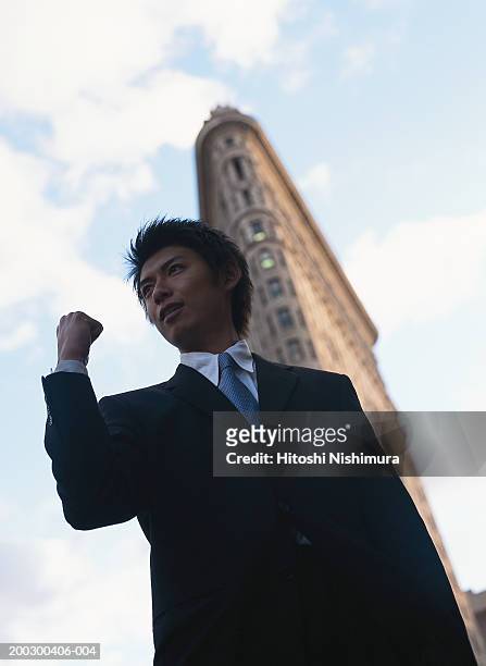 businessman clenching fist outdoors, low angle view - low motivation stock pictures, royalty-free photos & images