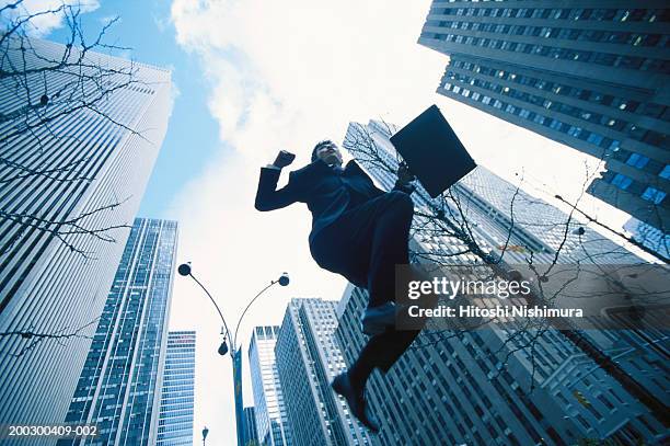 businessman jumping, low angle view - hochsprung stock-fotos und bilder