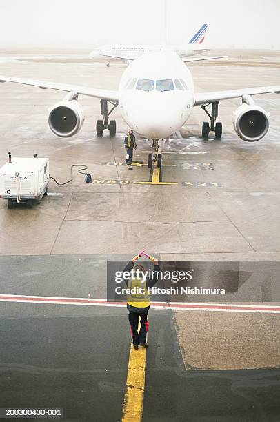 airport ground crew directing aircraft, elevated view - lotse stock-fotos und bilder