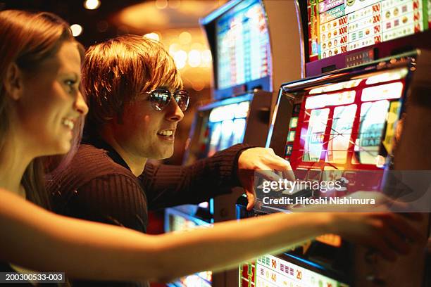 young couple playing slot machine - kansspel stockfoto's en -beelden