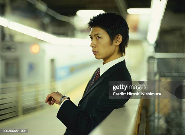 businessman on railway platform, side view - ongeduldig stockfoto's en -beelden