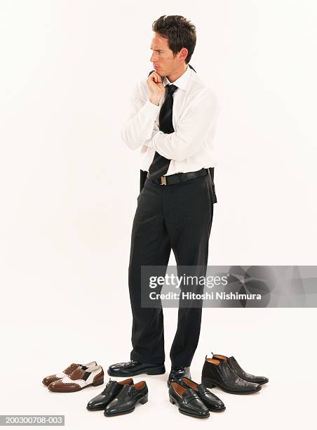 businessman standing in front of shoes, looking away - foot profile stock pictures, royalty-free photos & images