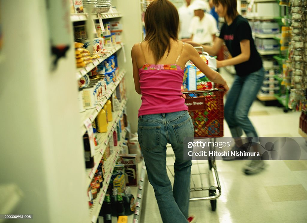 Woman with trolley in supermarket, rear view