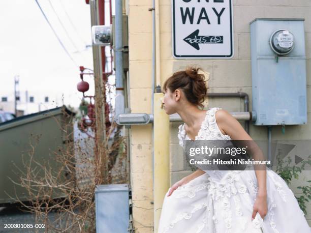 bride peeking around corner of building - runaway stock pictures, royalty-free photos & images