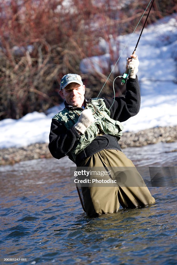 Man fishing in river reeling in fish