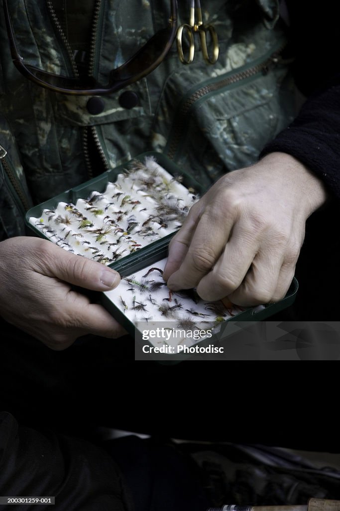 Fisherman choosing hook, close-up, mid section