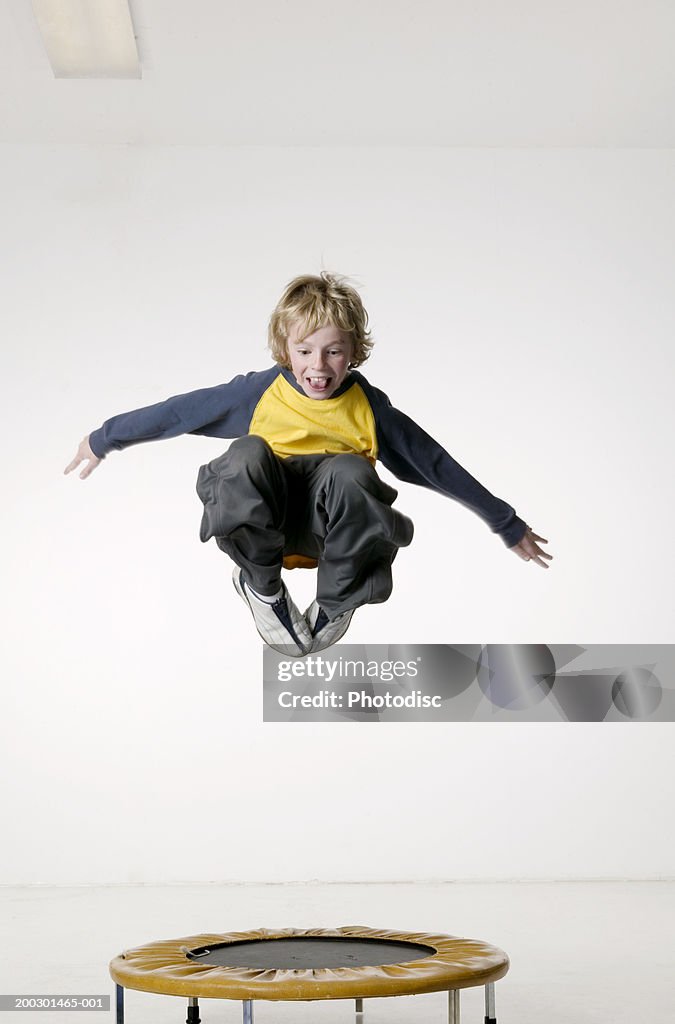 Young boy (8-9) jumping on small trampoline