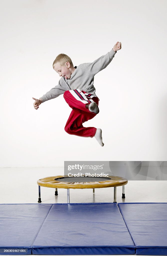 Young boy (8-9) jumping on small trampoline
