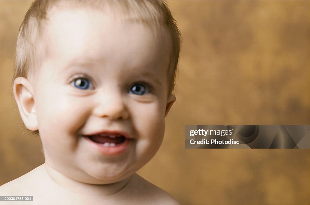 Amused baby boy (9-12 months) smiling, posing in studio, close-up, portrait