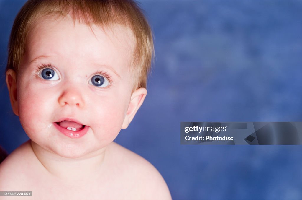 Amused baby boy (9-12 months) smiling, posing in studio, close-up, portrait