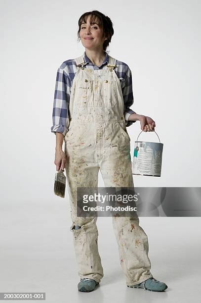 female painter in overalls holding brush and paint bucket - overall stock pictures, royalty-free photos & images