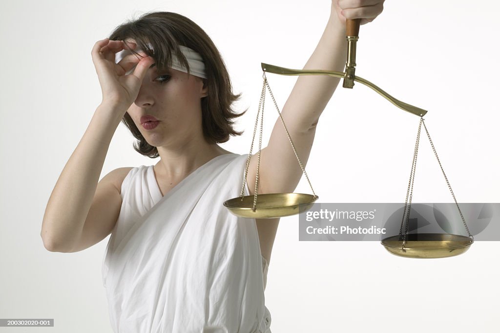 Woman dressed as lady justice peeking at scales