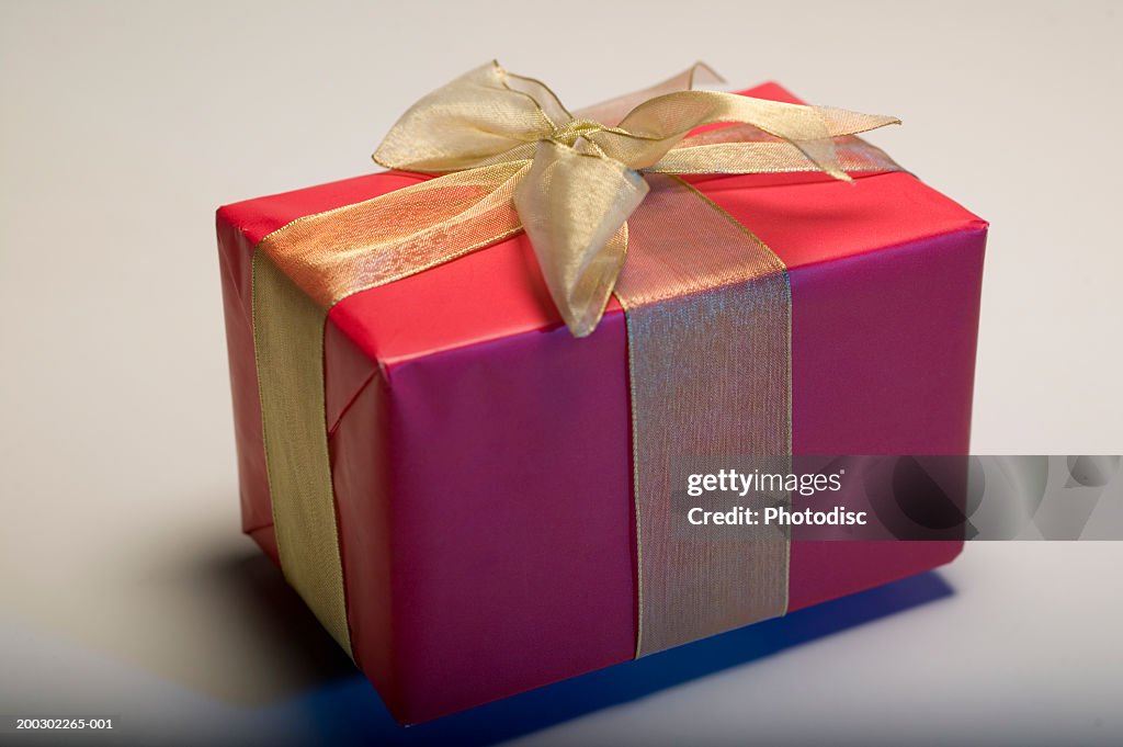 Gift wrapped in paper and ribbon against white background, close-up