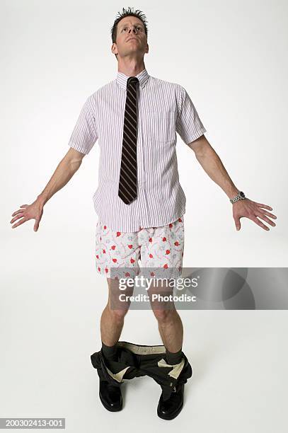 young man standing in studio with trousers around ankles - trousers down stock pictures, royalty-free photos & images