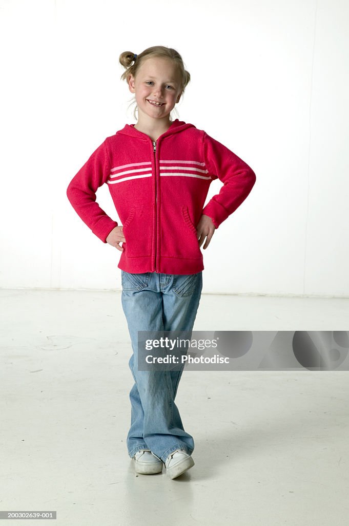 Girl (6-7), with hands on hips, posing in studio, portrait