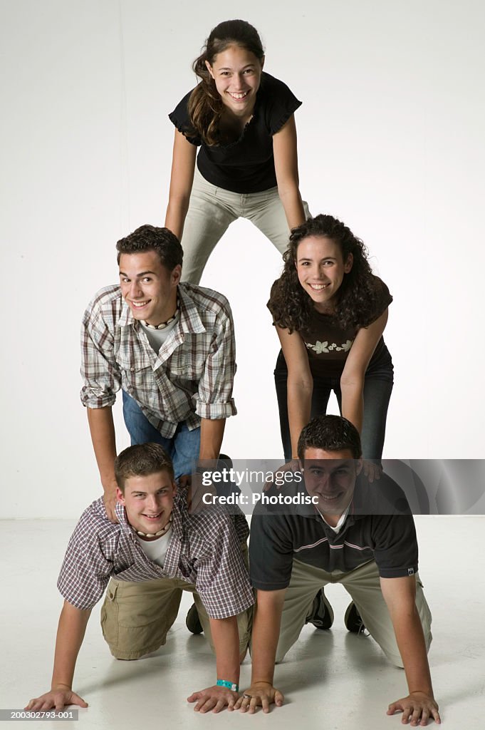 Five young friends forming pyramid, posing in studio, portrait